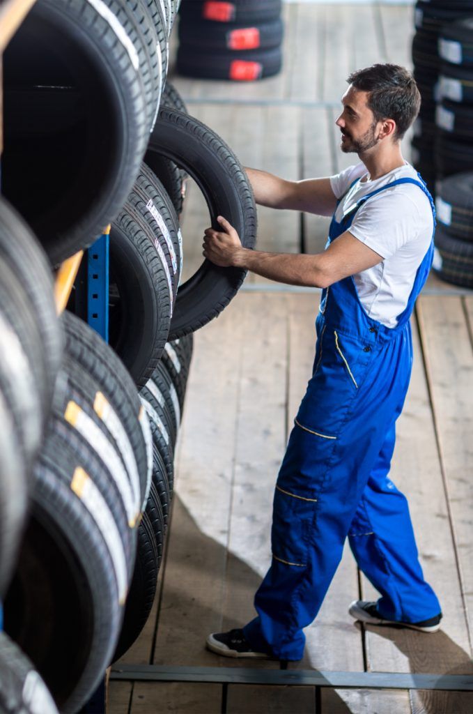 Mechanic taking a tyre from stock - Tyres Saltney, Chester